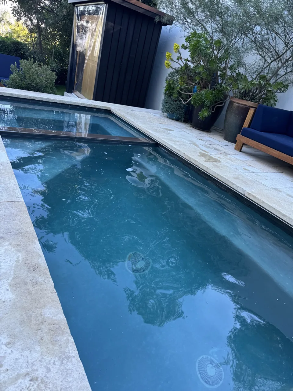 Courtyard lap pool with blue water and a raised square spa