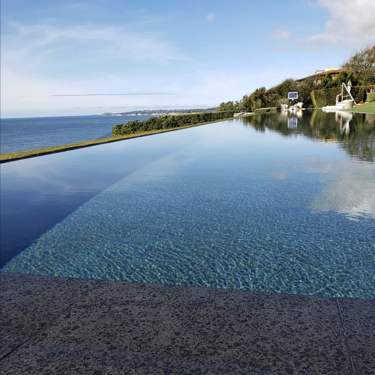 Infinity-edge pool with clear blue water overlooking the ocean on a sunny day