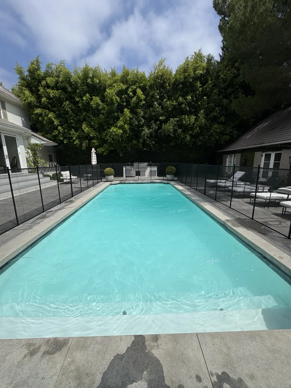 Matching rectangular fenced pool with turquoise water and visible entry steps